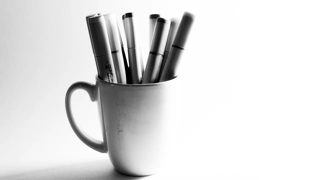 Pens standing in a white mug, photographed in black and white